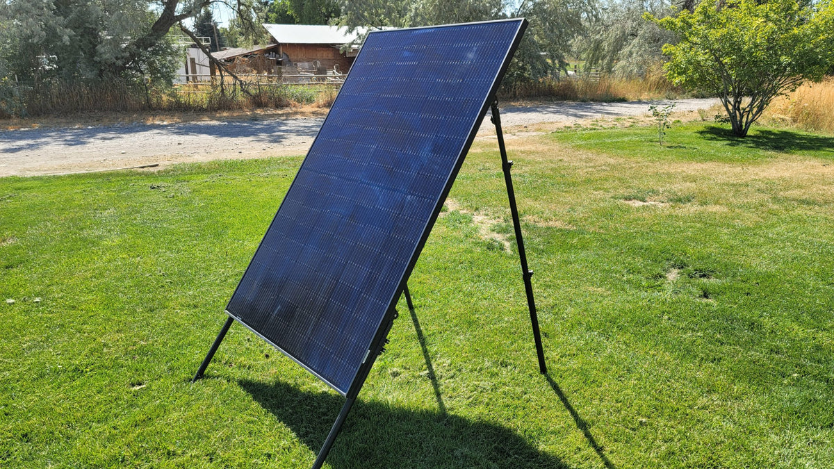 Tilted solar panel on adjustable stand legs in a yard